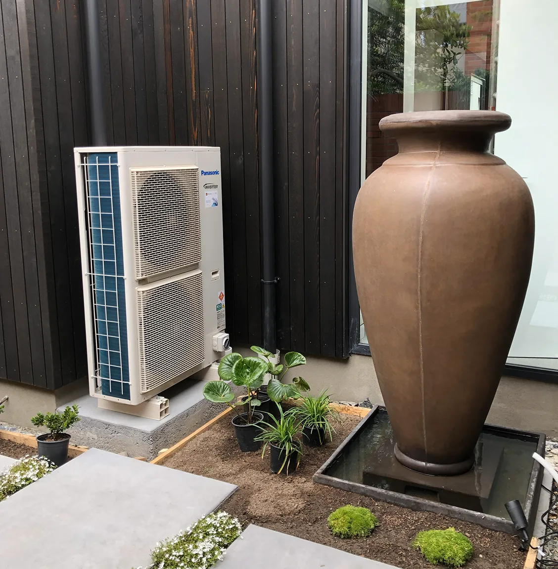 dual fan hot water heat pump installed in a residential property by PolarEnergi NZ, next to a classic vase