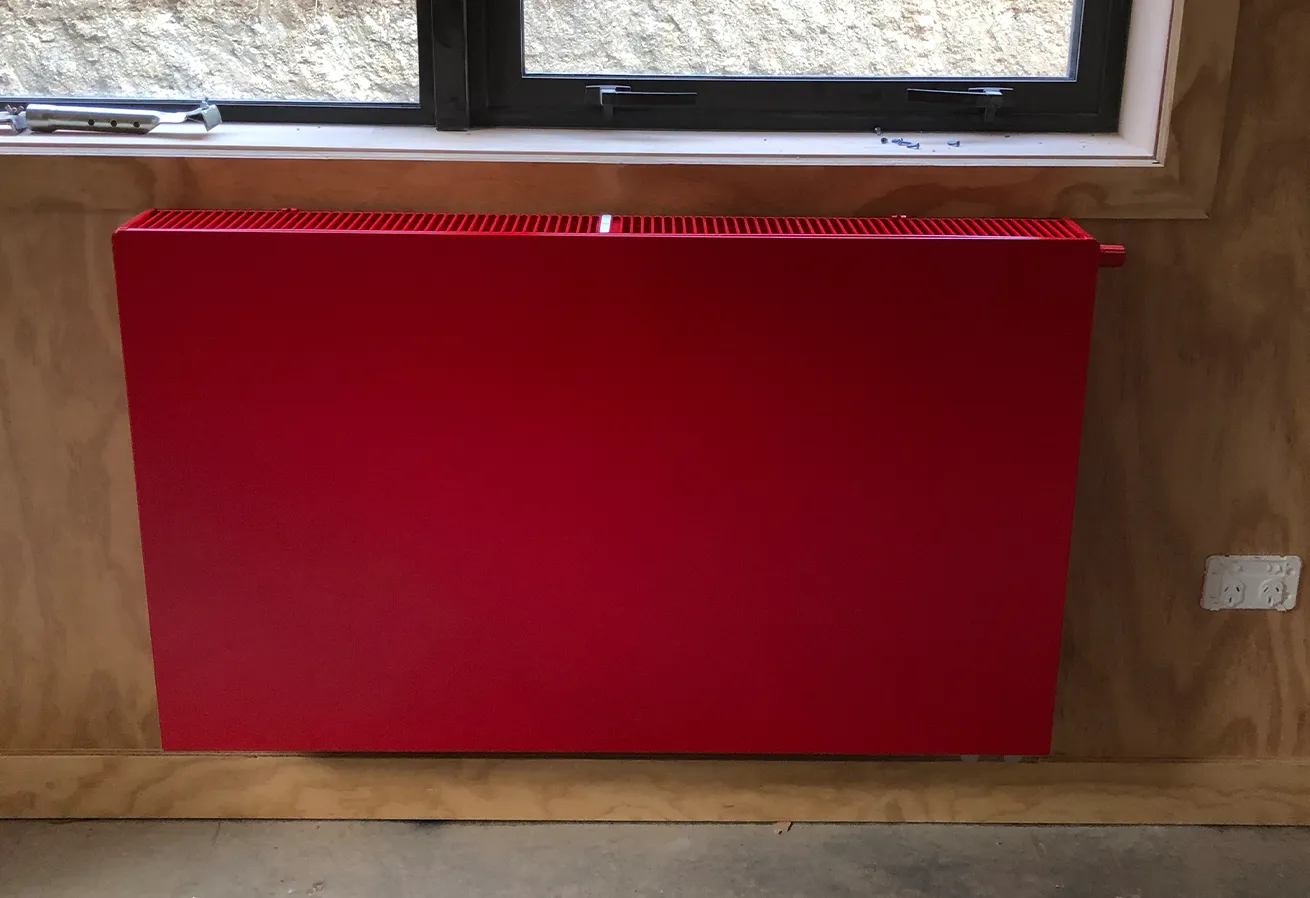 wall mounted red coloured radiator installed by PolarEnergi NZ